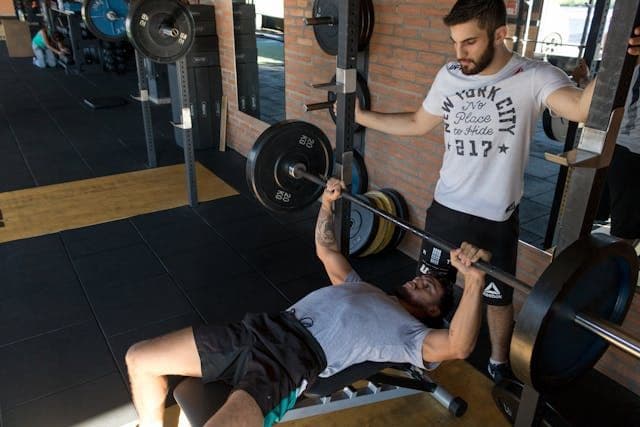 entrenador personal con barras entrenando pecho
